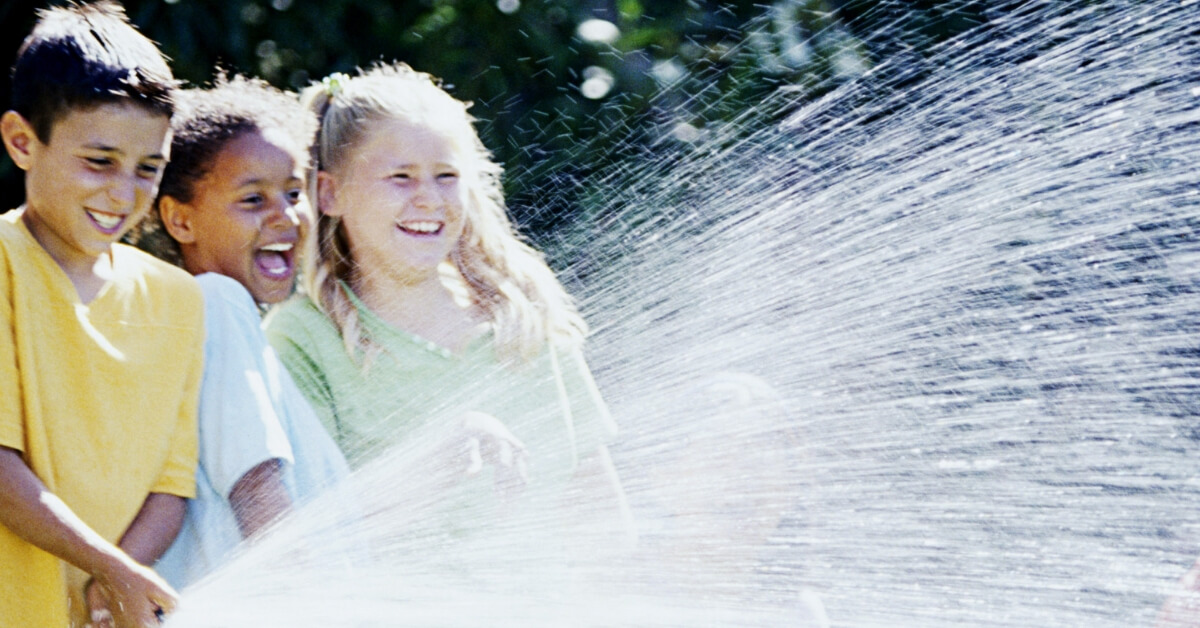 three kids playing with a hose