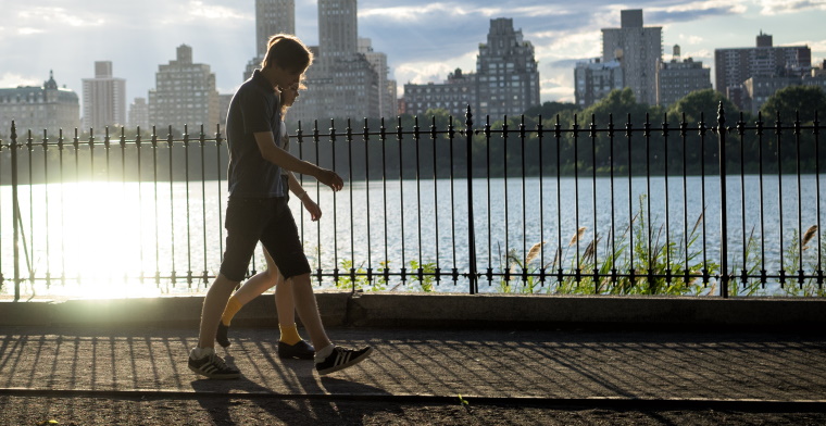 photo of two people walking beside the water