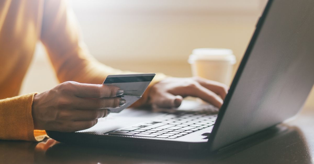 photo of a woman's hand holding a credit card as she sits at her laptop. Online shopping may increase after COVID-19