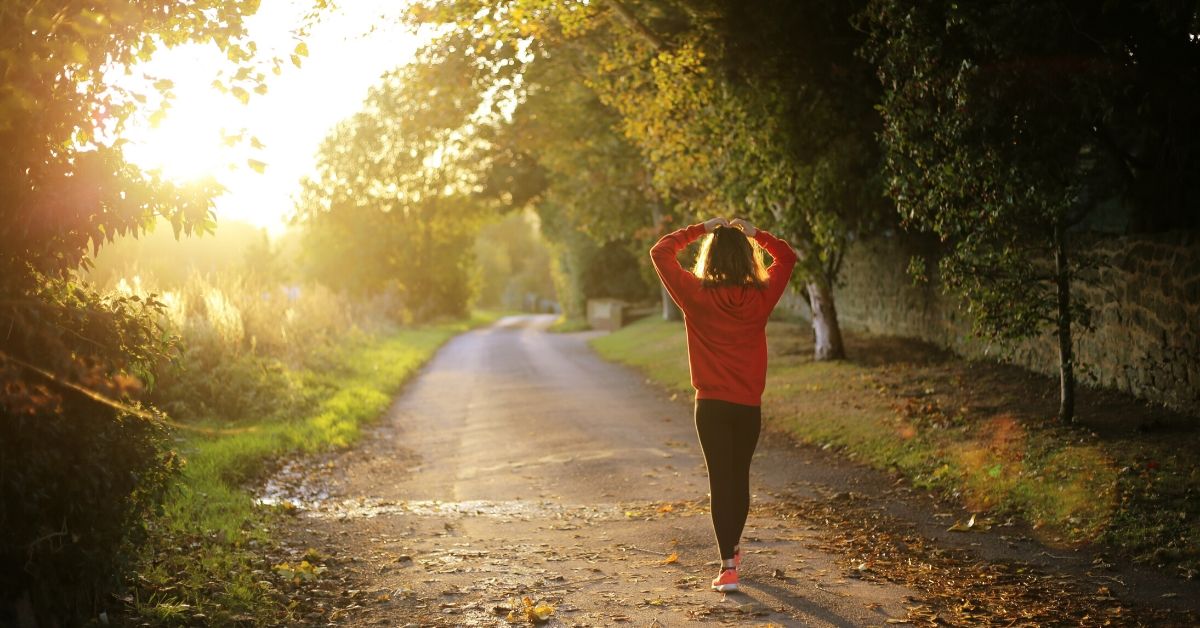photo of a woman walking in a park at sunrise